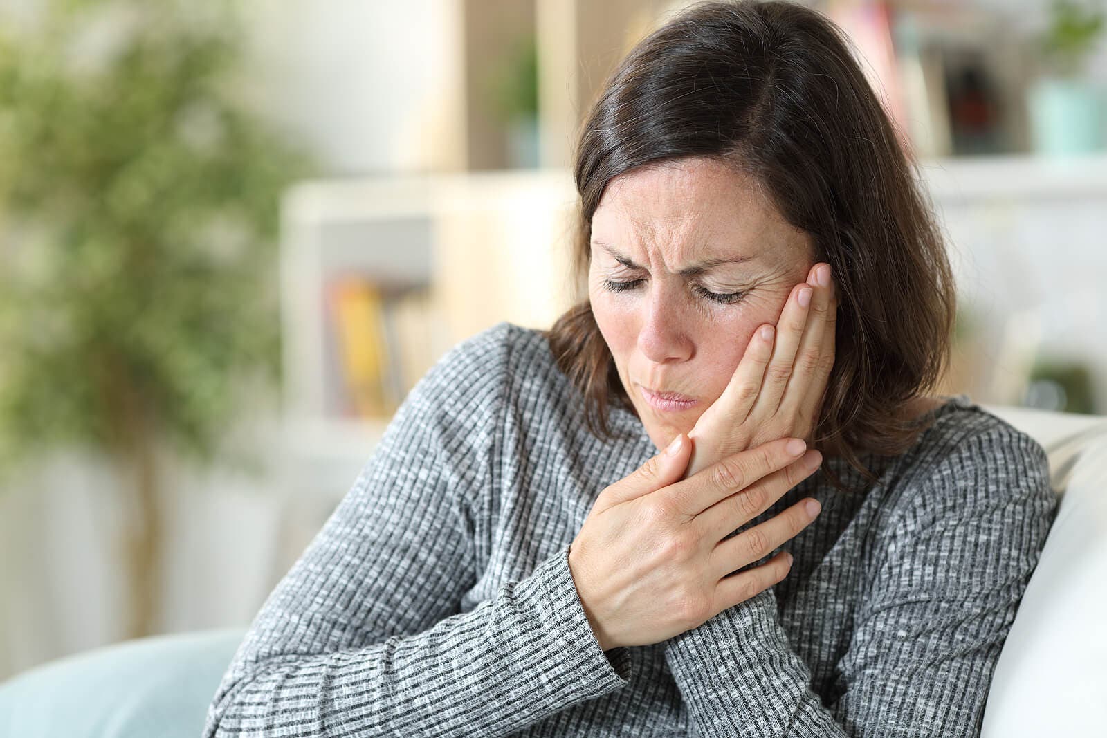 Mujer sentada con dolor mandibular.