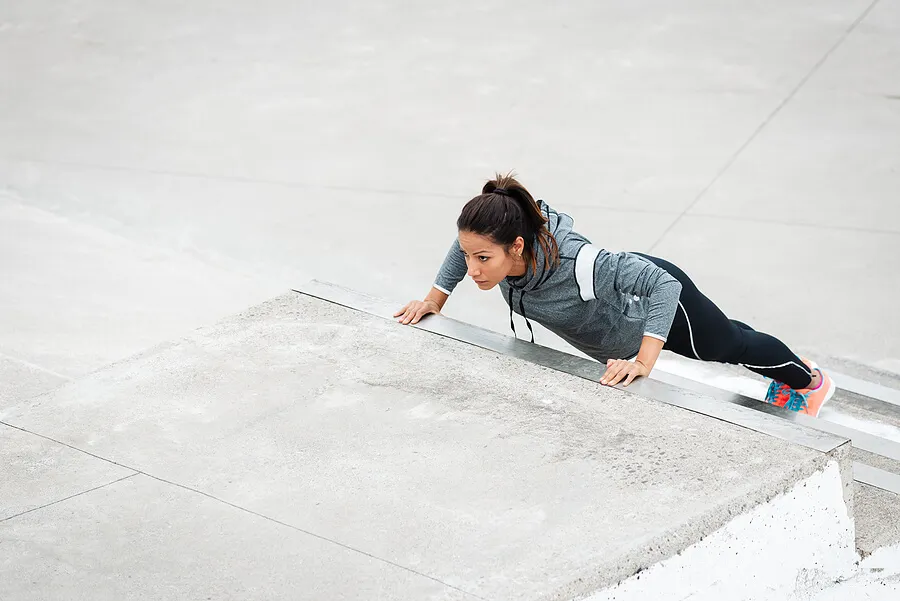 Mujer haciendo flexiones en las escaleras.