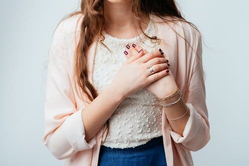 En kvinne som holder brystet hennes.