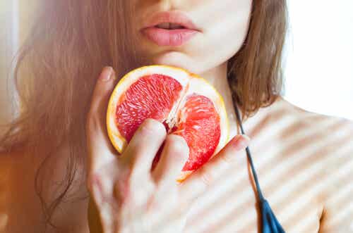 Kvinde holder appelsin på en seksuel måde