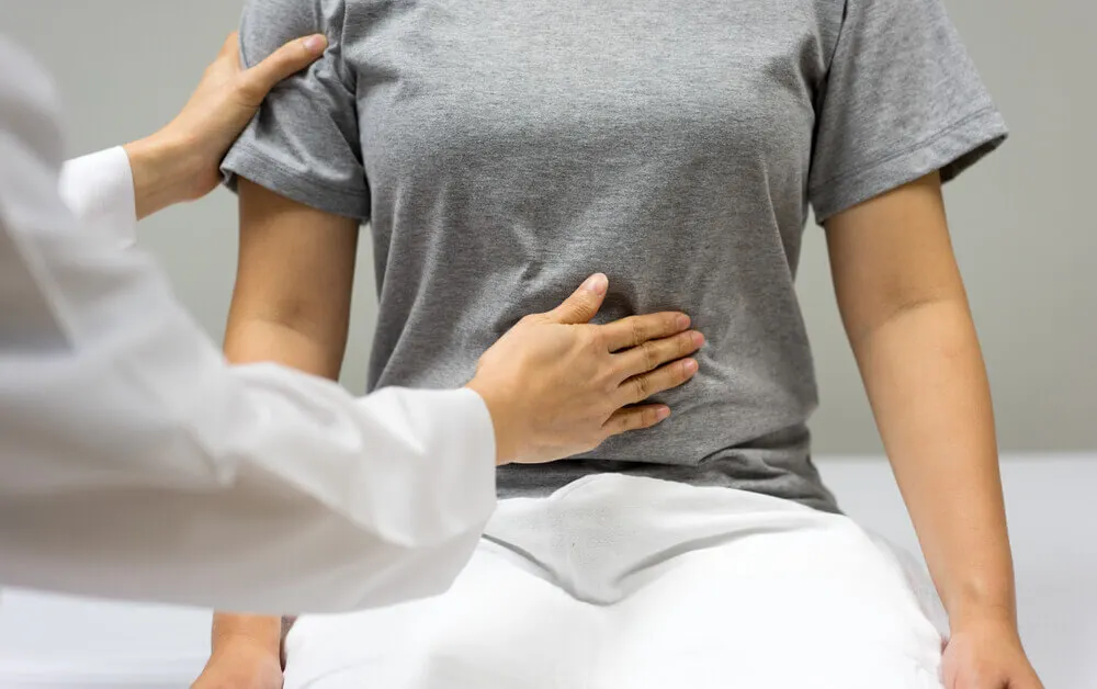 Médico palpando el abdomen de un paciente.
