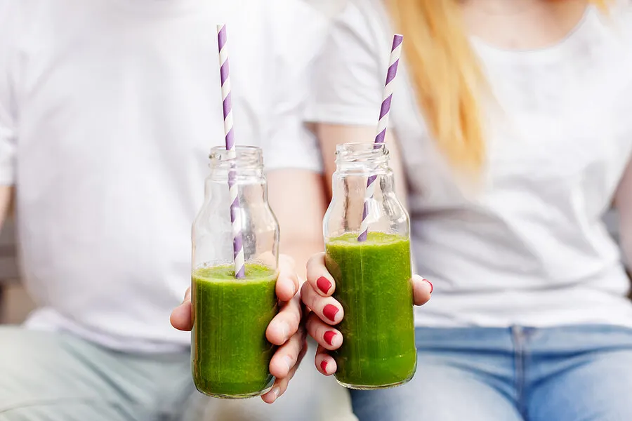 Personas con botellas de batidos verdes.