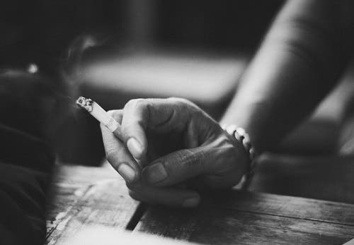 Mano sosteniendo un cigarrillo encendido.