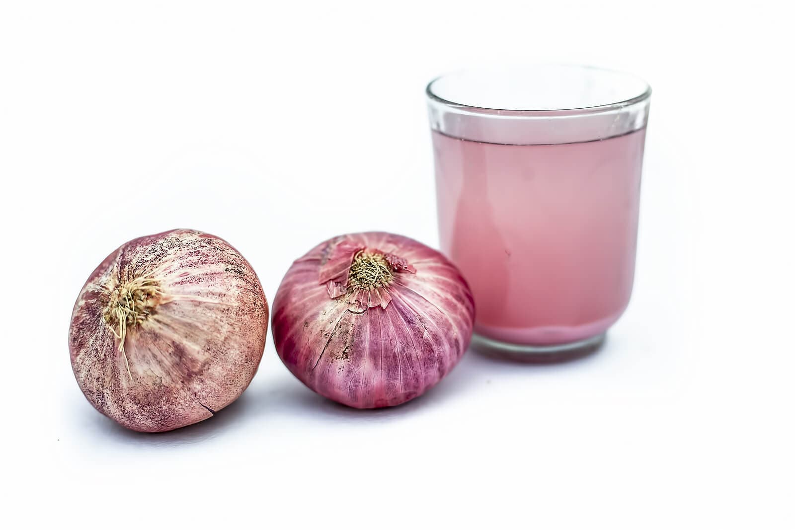 Vaso con jugo de cebolla y ajo morado.