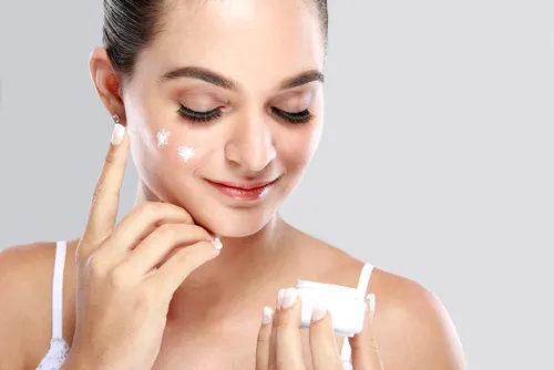 Mujer aplicándose una crema en el rostro.