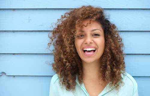 mujer feliz con pelo rizando sonriendo a la cámara