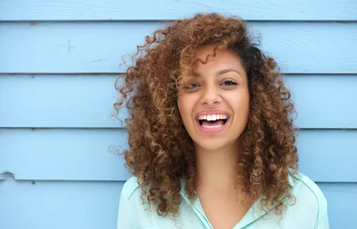 mujer feliz con pelo rizando sonriendo a la cámara