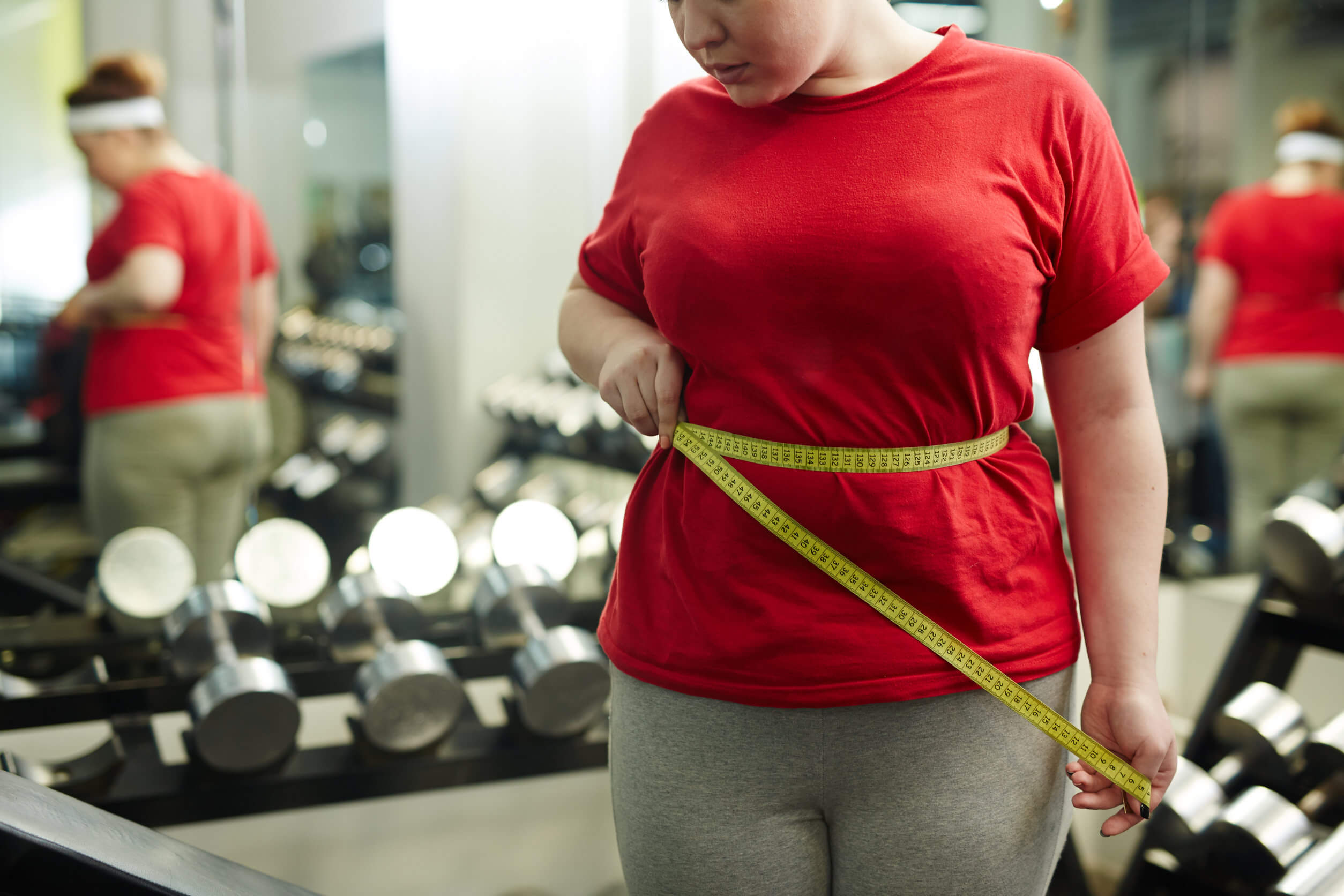 Mujer con sobrepeso mide su cintura.