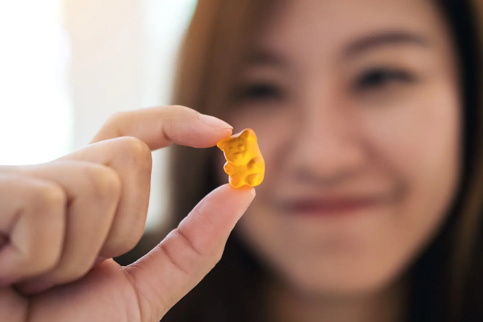 Mujer sujetando un osito de goma de miel y cúrcuma.