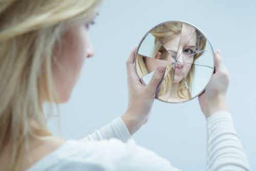 Mujer mirándose en un espejo roto simbolizando la baja autoestima por el maltrato psicológico