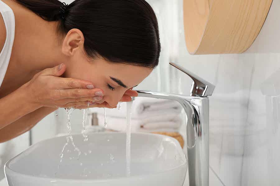 Mujer lavándose el rostro en el lavabo.