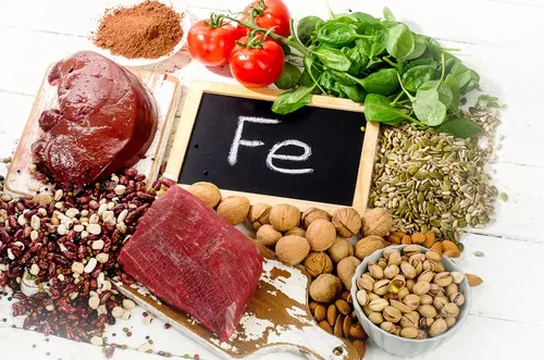 Alimentos con hierro y una pizarra con la leyenda Fe