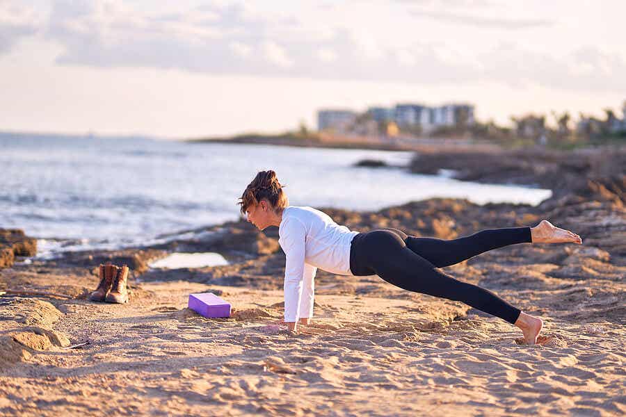 Mujer haciendo yoga en la playa.