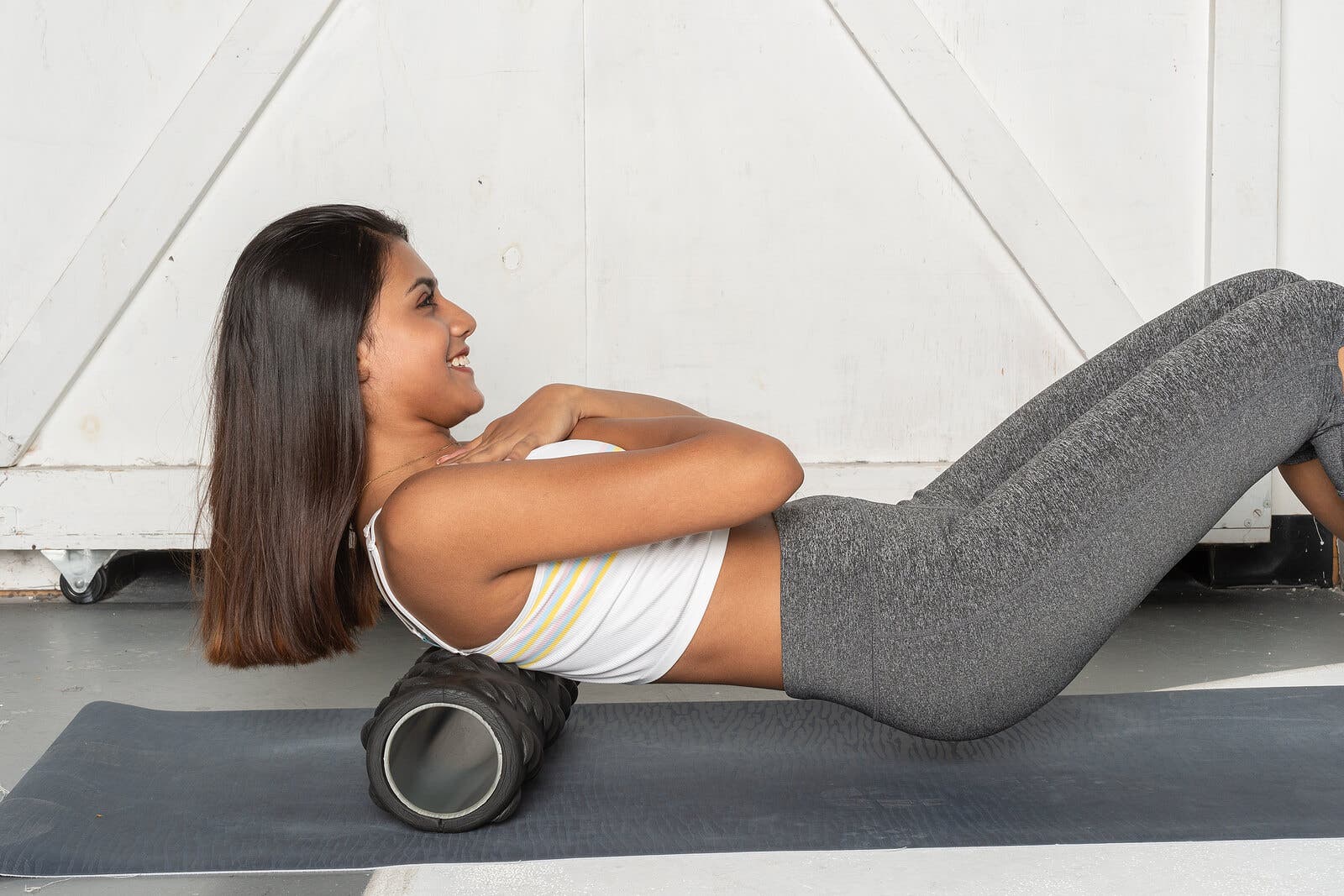 Chica usando un masajeador de espuma después del entrenamiento.