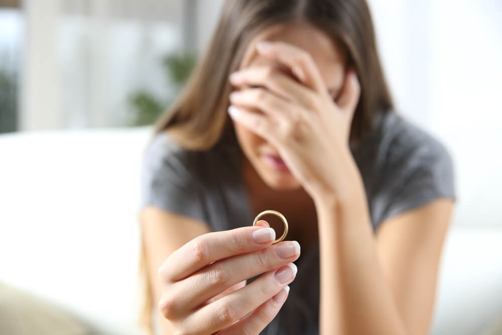 Mujer llorando con un anillo en la mano