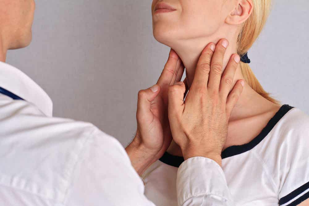 Médico palpando la tiroides (glándulas endocrinas) de una mujer.