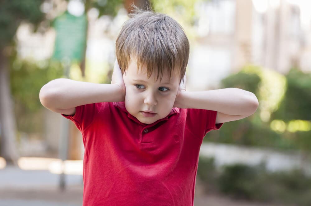 Niño tapándose los oídos.