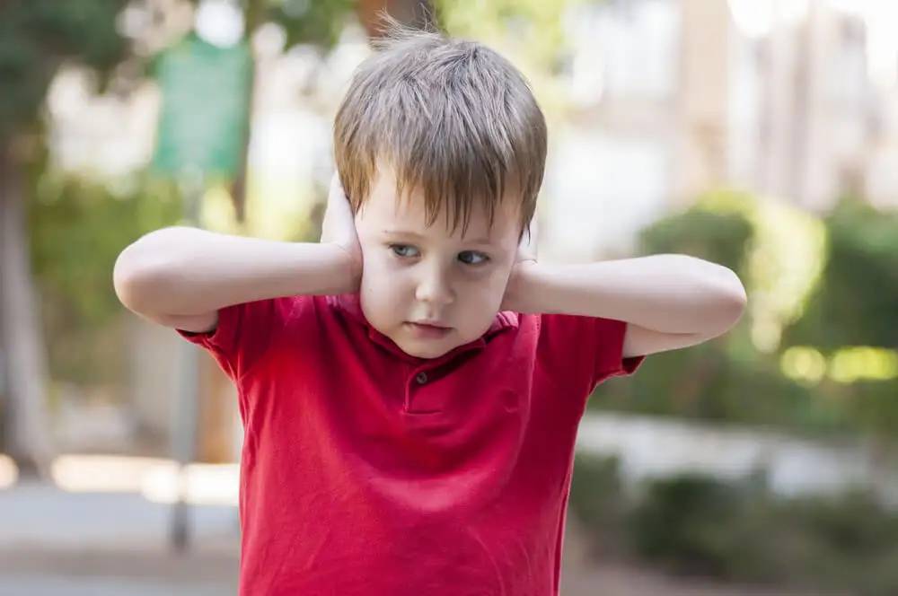 Niño tapándose los oídos.