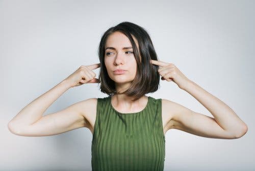 Mujer tapándose los oídos del ruido.