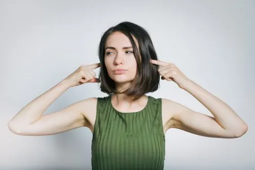 Mujer tapándose los oídos del ruido.
