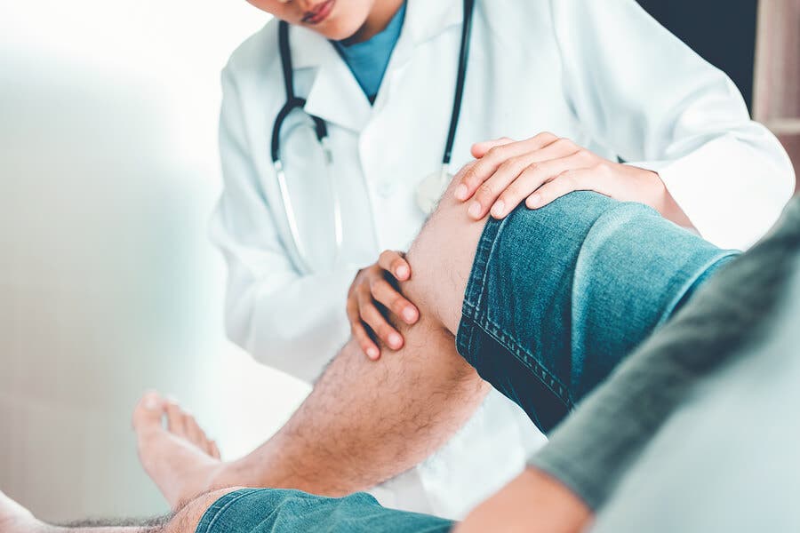 Médico examinando la rodilla de un paciente.