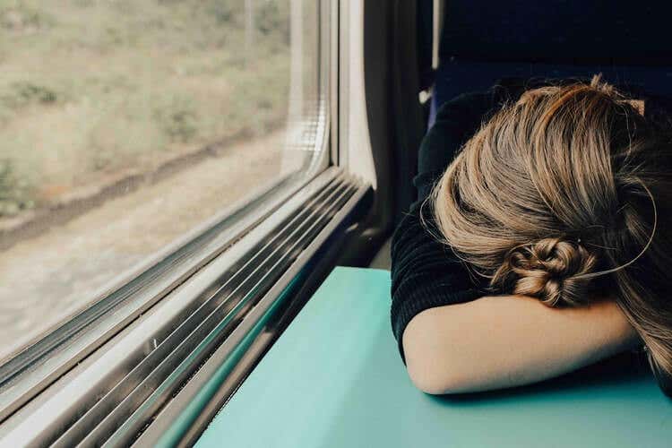 Femme affalée sur une table dans un train.