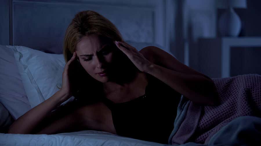 Mujer despertándose con dolor de cabeza nocturno.