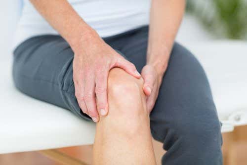 Hombre tocándose la rodilla: Osteoartritis de rodilla