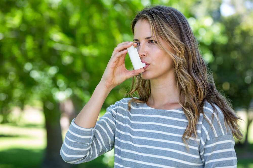 Mujer usando el inhalador debido al asma que sufre