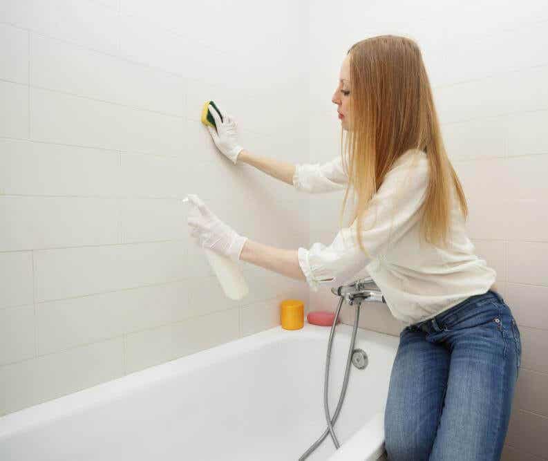 Femme qui nettoie un mur de la salle de bain.