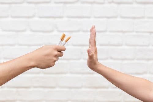 Mano rechazando unos cigarrillos: tabaquismo