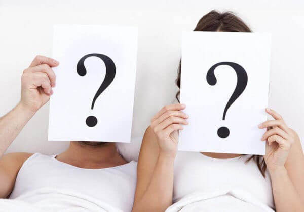 Pareja en la cama con signos de interrogación