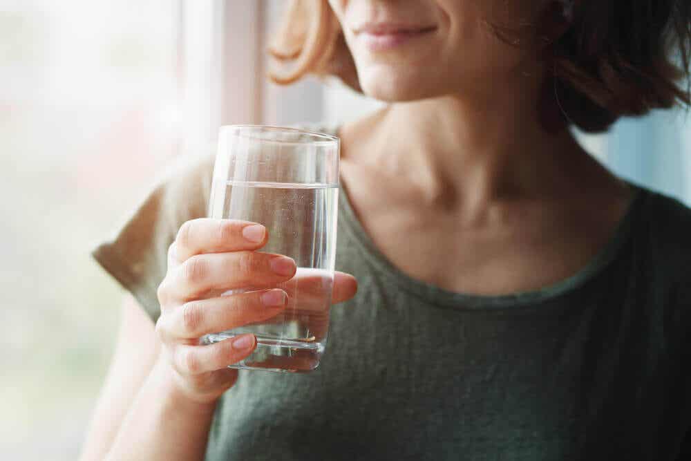 Mujer sosteniendo un vaso con agua que va a beber.