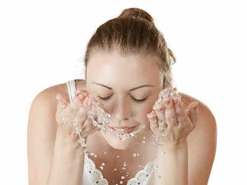 Chica limpiando su rostro con agua pura tras aplicarse el jabón antiacné.