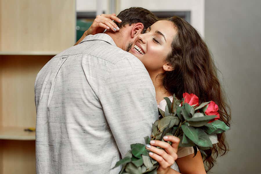 Mujer abrazando a hombre con flores.