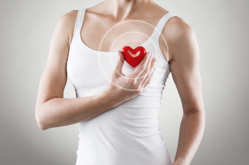 Mujer sosteniendo un corazón de goma, indicando salud.