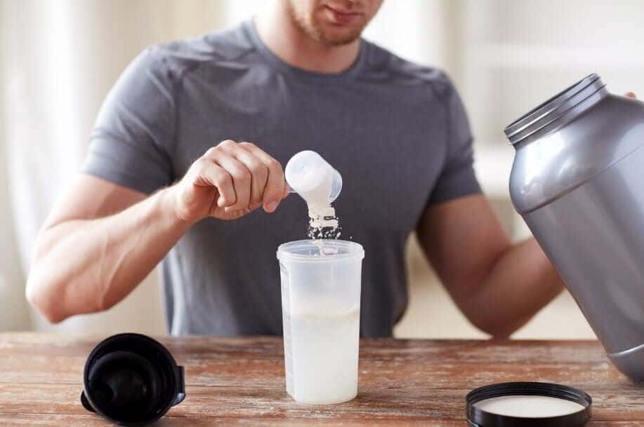 Hombre haciéndose un batido de proteínas con suero de leche.