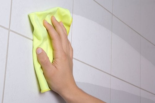 Mano limpiando la pared con un trapo