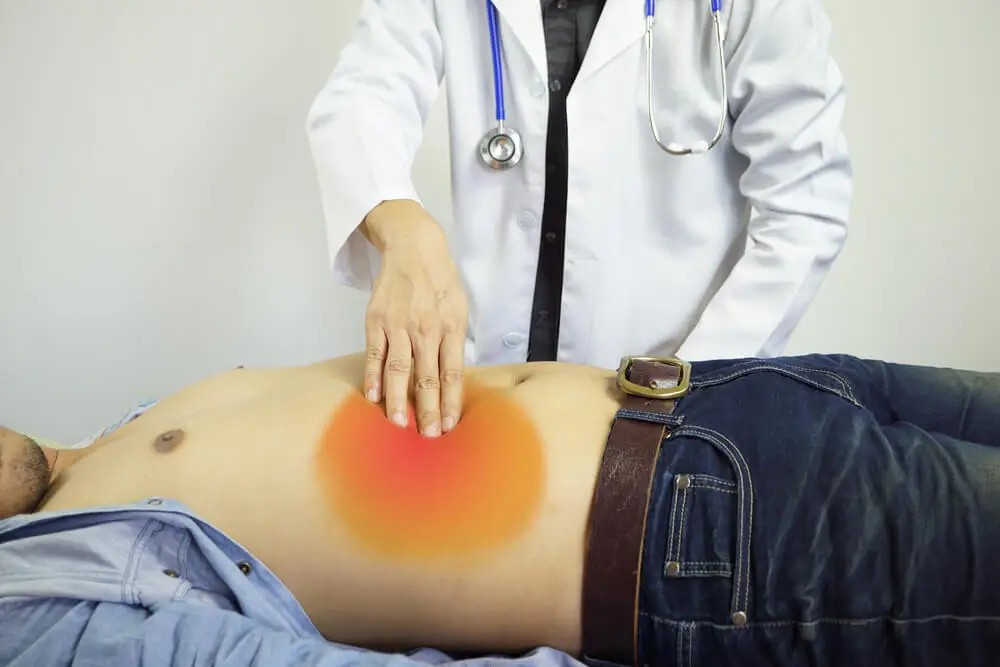 Médico examinando abdomen de paciente.