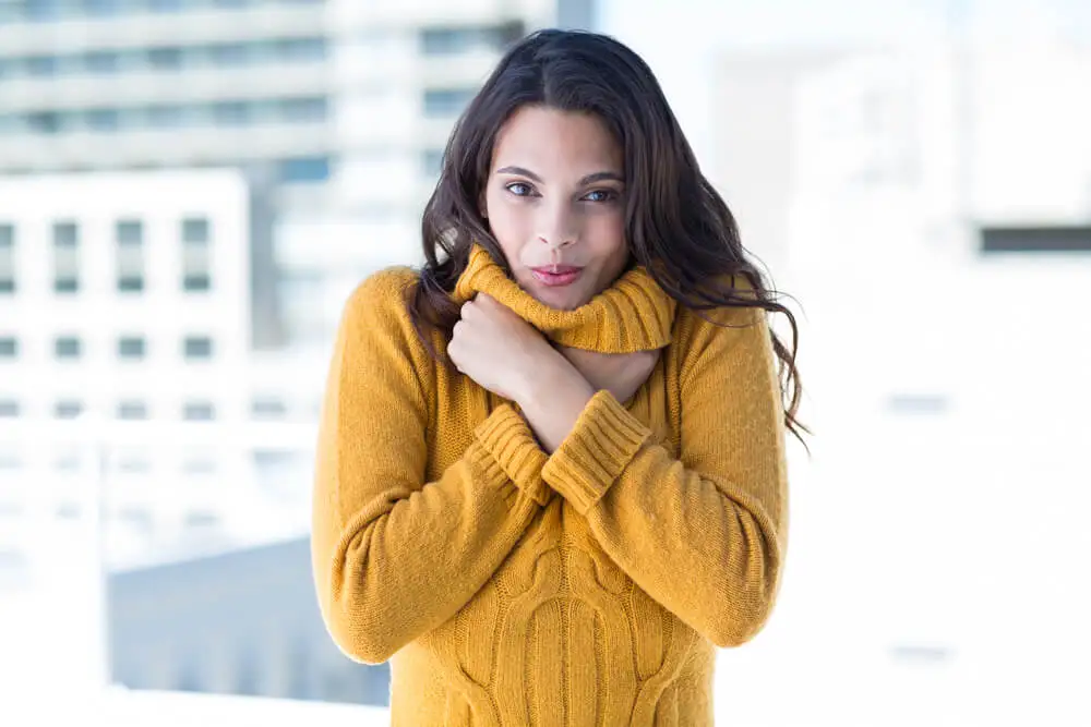 Mujer abrigándose porque siente frío