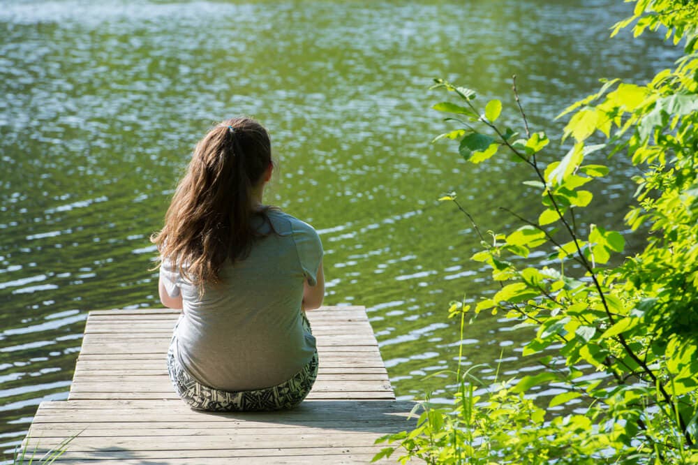 Femme seule au bord d'une rivière.