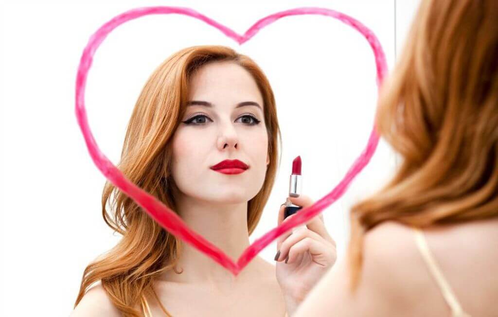Chica mirándose en un espejo con un pintalabios