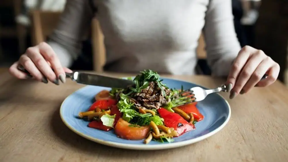 Mujer en la mesa siguiendo una buena alimentación