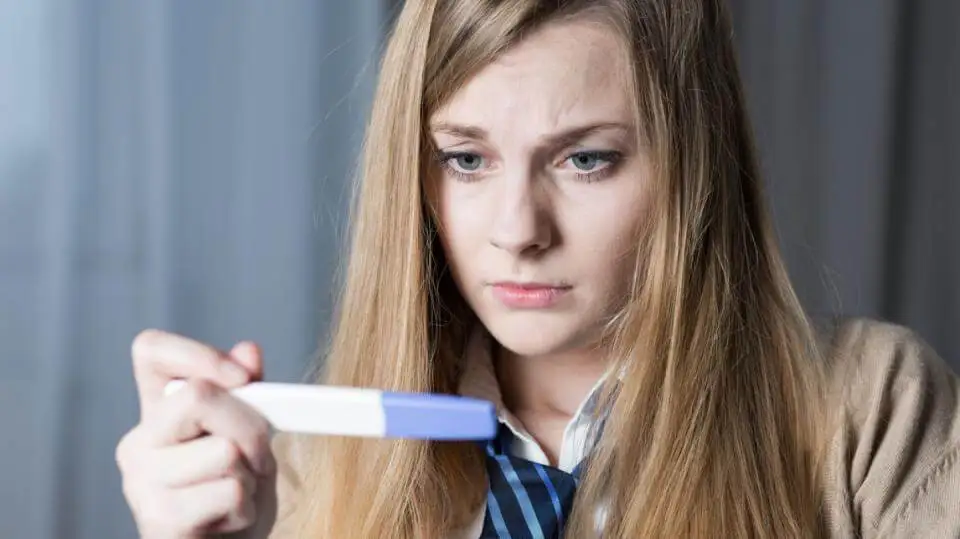 Mujer mirando un test de embarazo. Tipos de aborto.