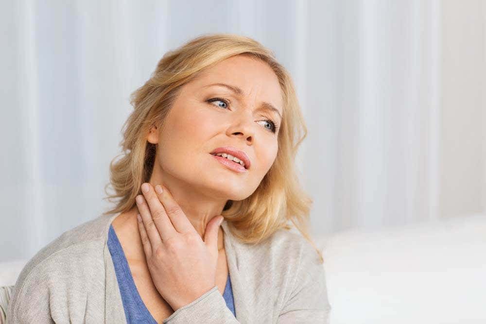 unhappy woman suffering from throat pain at home