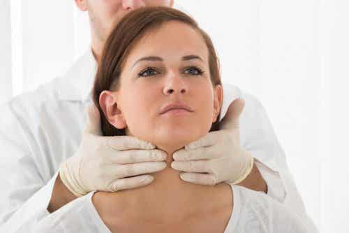Médico auscultando la tiroides de una mujer