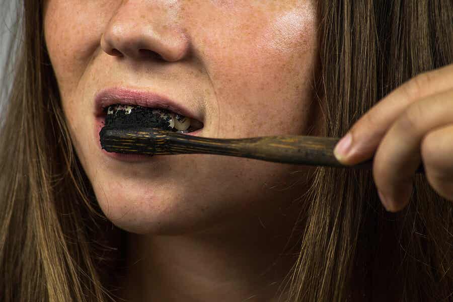 Mujer cepillándose los dientes con carbona activado.
