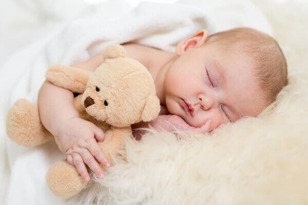 Bebé durmiendo plácidamente abrazado a un peluche.