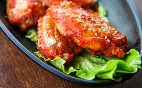Alitas de pollo con salsa y lechuga.