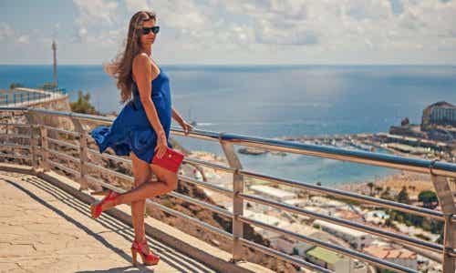 Chica posa con un vestido azul y zapatos de tacón rojos.